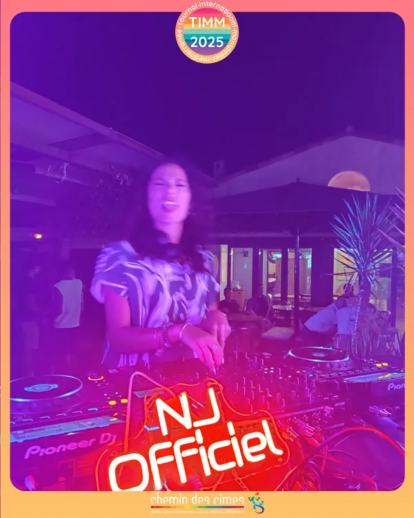 NJ mixe aux platines sous une lumière violette, derrière l'enseigne lumineuse NJ Officiel.